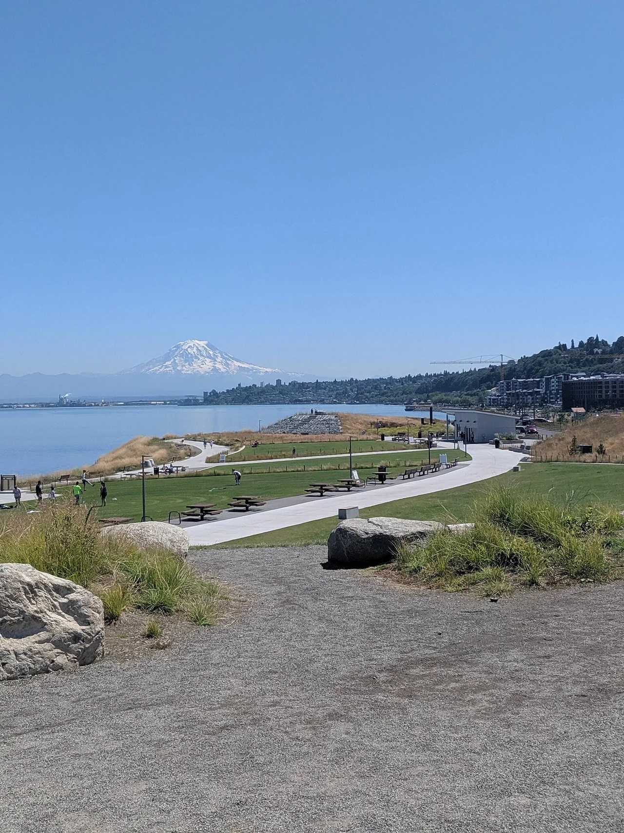 Gravel paths and shoreline planting at Dune Peninsula, with water and Mount Rainier in the distance.